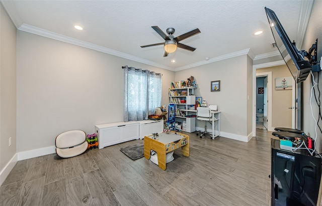 game room featuring ornamental molding, light wood-type flooring, a textured ceiling, and ceiling fan