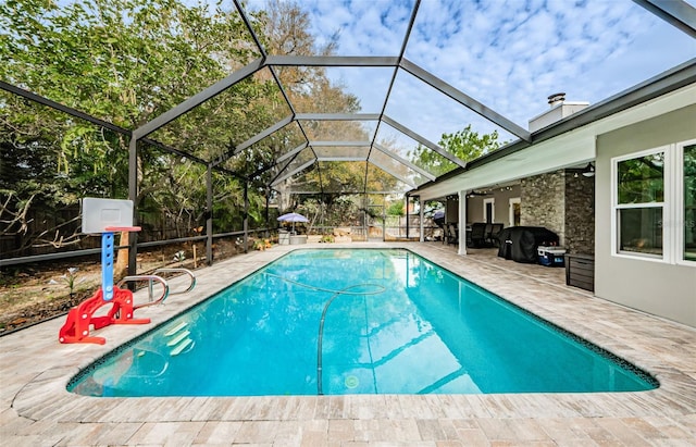 view of swimming pool with grilling area, a patio area, and glass enclosure