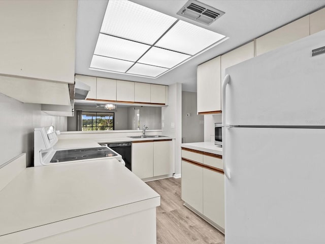 kitchen with light wood-style flooring, white appliances, a sink, visible vents, and light countertops