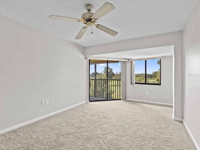 carpeted spare room featuring ceiling fan, baseboards, and a textured ceiling