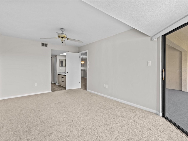 empty room featuring visible vents, baseboards, ceiling fan, a textured ceiling, and carpet floors