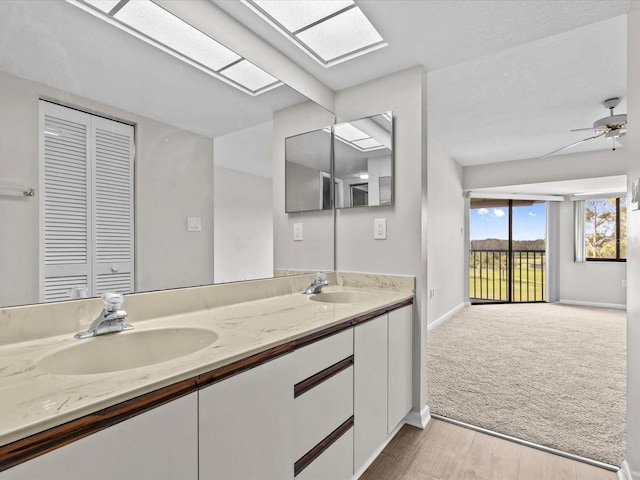 bathroom featuring double vanity, a skylight, a sink, and a ceiling fan