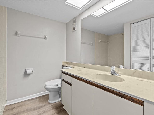 full bath featuring a skylight, visible vents, tiled shower, toilet, and wood finished floors