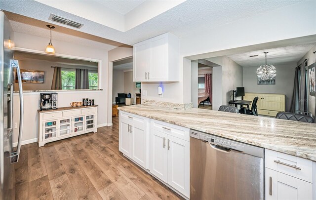 kitchen with light wood-type flooring, stainless steel appliances, a chandelier, and white cabinetry