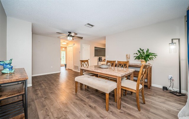 dining room featuring dark wood-type flooring, a textured ceiling, and ceiling fan