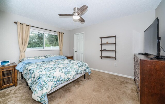 bedroom featuring ceiling fan, light colored carpet, and a textured ceiling