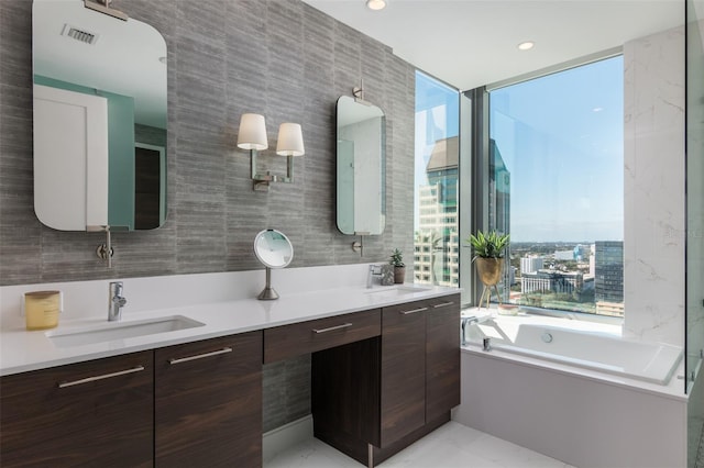 bathroom with tile walls, tile patterned flooring, a bathing tub, and vanity