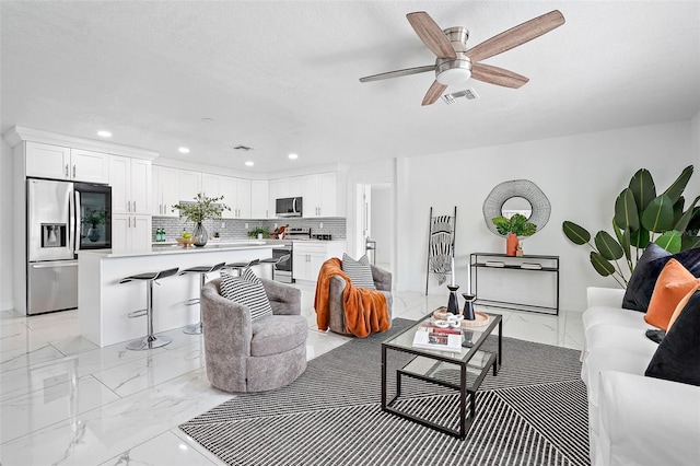 living room featuring ceiling fan and a textured ceiling