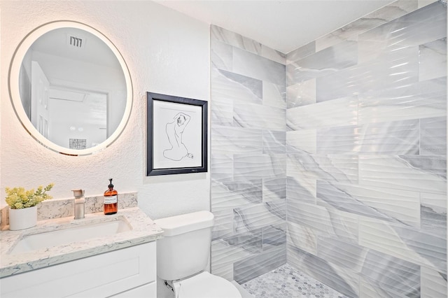 bathroom with vanity, toilet, and a tile shower