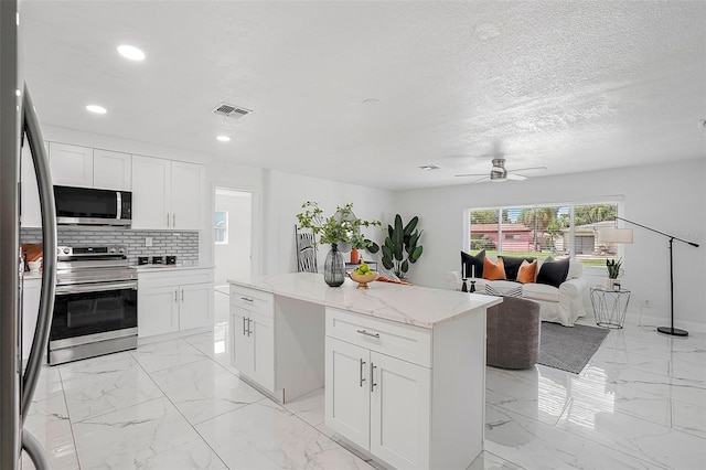 kitchen featuring ceiling fan, a center island, white cabinets, and appliances with stainless steel finishes