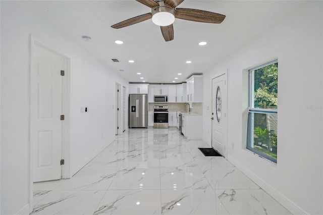 kitchen with white cabinets, stainless steel appliances, and ceiling fan