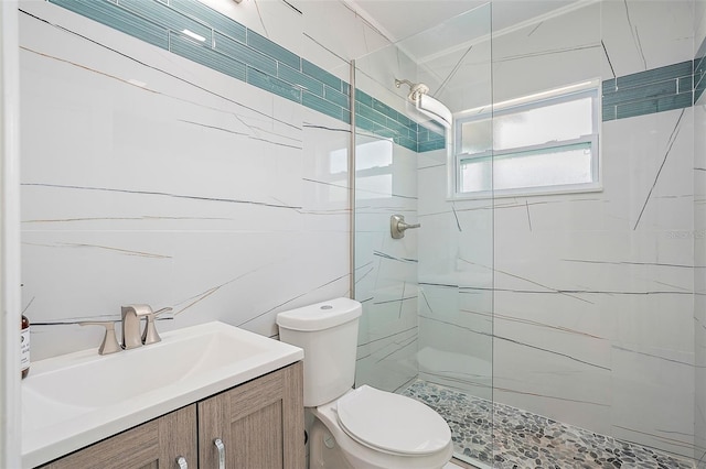 bathroom featuring vanity, toilet, tile walls, and a tile shower