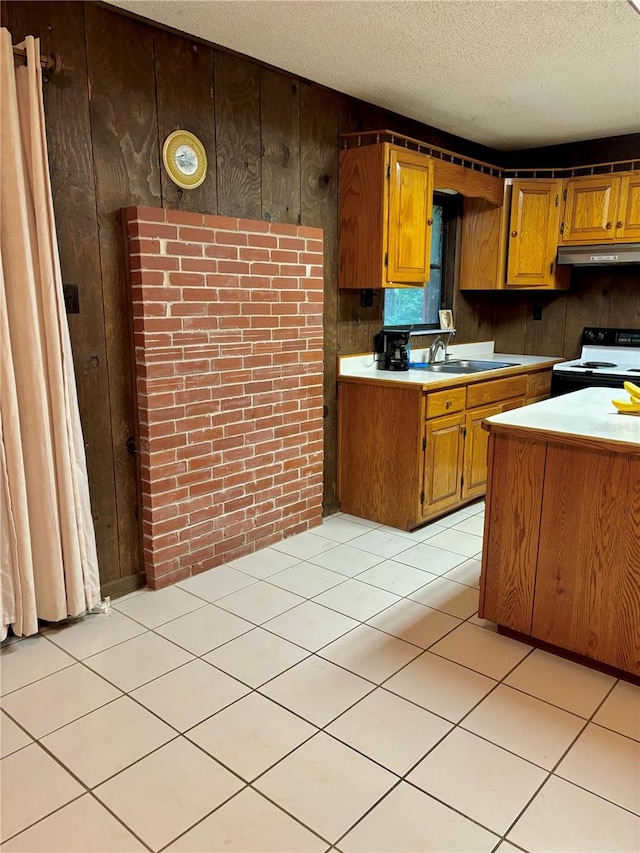 kitchen featuring light tile patterned floors, sink, electric stove, wood walls, and a textured ceiling