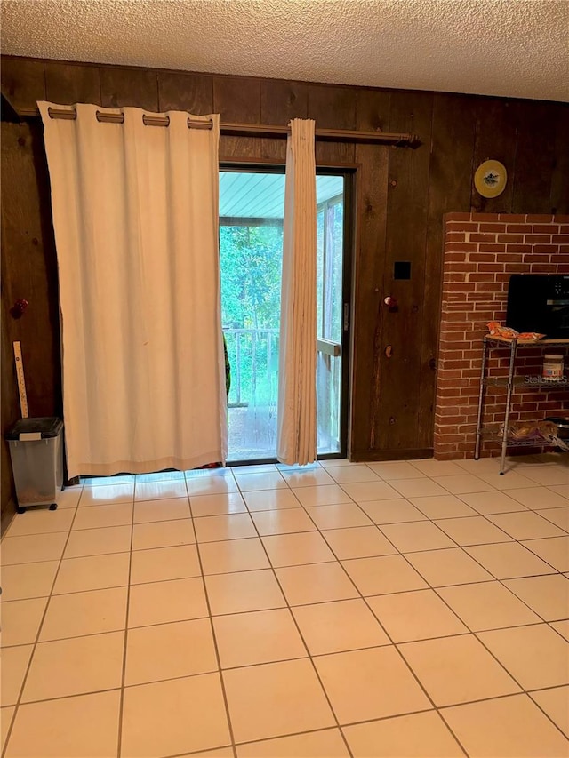 interior space featuring wood walls, a textured ceiling, and light tile patterned flooring