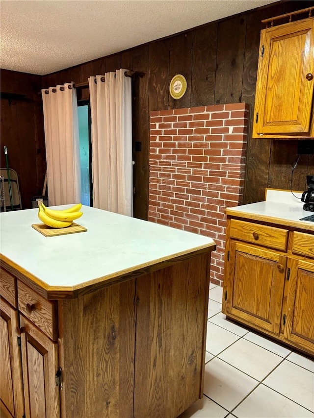 kitchen featuring light tile patterned floors, a kitchen island, wooden walls, and a textured ceiling