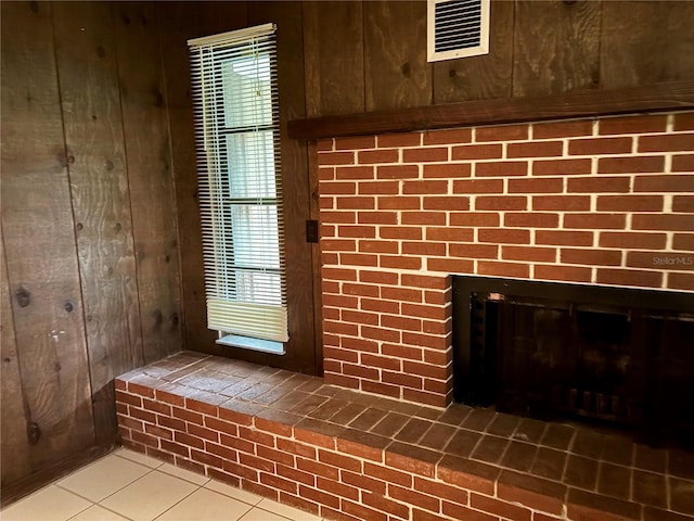 room details featuring wooden walls, tile patterned floors, and a fireplace