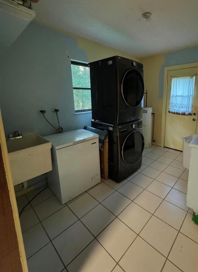 washroom with light tile patterned floors, stacked washer / drying machine, and sink