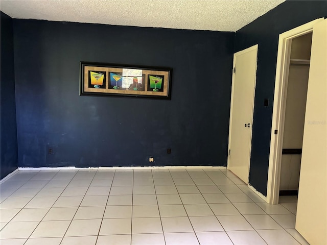 empty room featuring a textured ceiling and light tile patterned floors