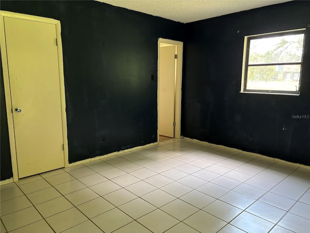 tiled empty room featuring a textured ceiling