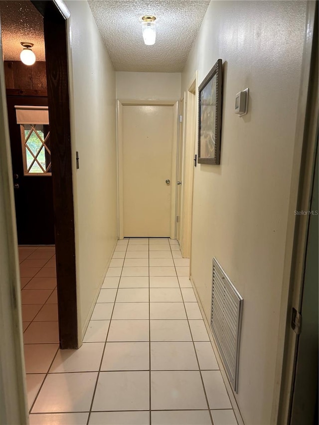 corridor featuring a textured ceiling and light tile patterned flooring