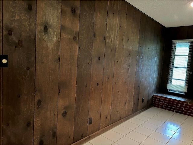 interior space featuring wood walls, tile patterned flooring, and a textured ceiling