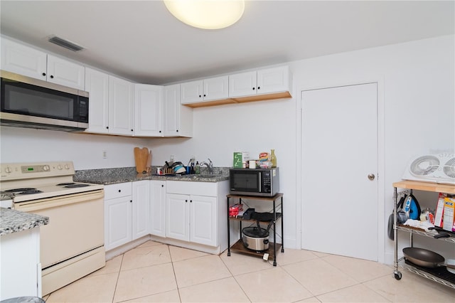 kitchen featuring white cabinetry, sink, dark stone counters, white electric range oven, and light tile patterned floors