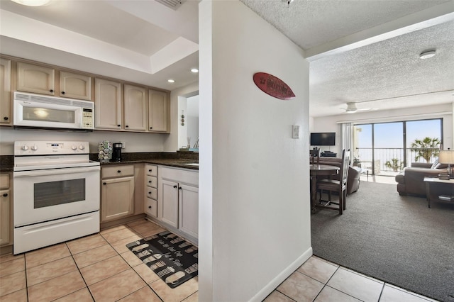 14950 Gulf Blvd Unit 404, Madeira Beach, FL 33708 - kitchen featuring white appliances, open floor plan, light tile patterned floors, dark countertops, and a textured ceiling