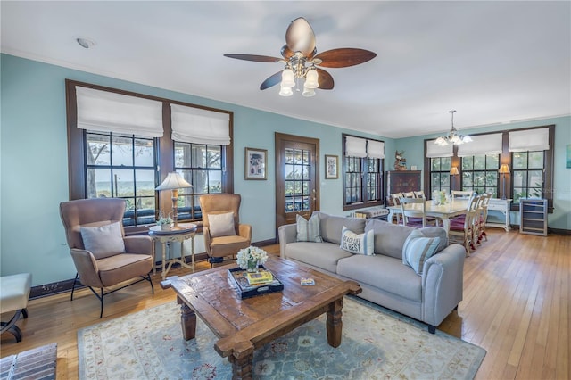 living room with crown molding, light hardwood / wood-style flooring, ceiling fan, and a wealth of natural light