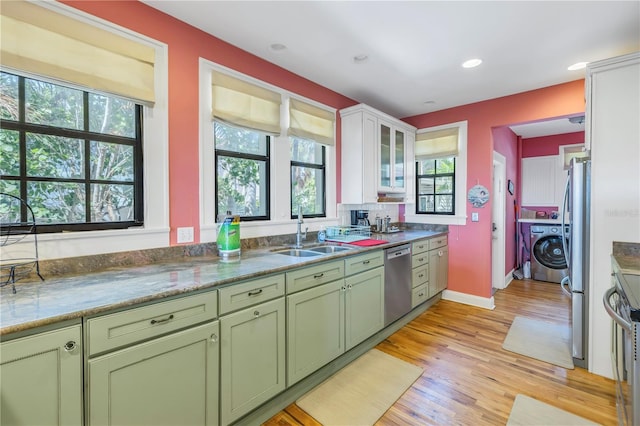 kitchen featuring light hardwood / wood-style floors, green cabinetry, sink, appliances with stainless steel finishes, and washer / clothes dryer