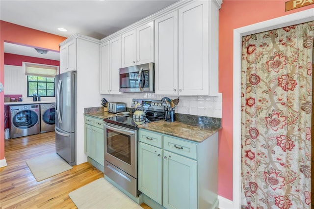 kitchen with washer and clothes dryer, backsplash, appliances with stainless steel finishes, light hardwood / wood-style floors, and white cabinetry