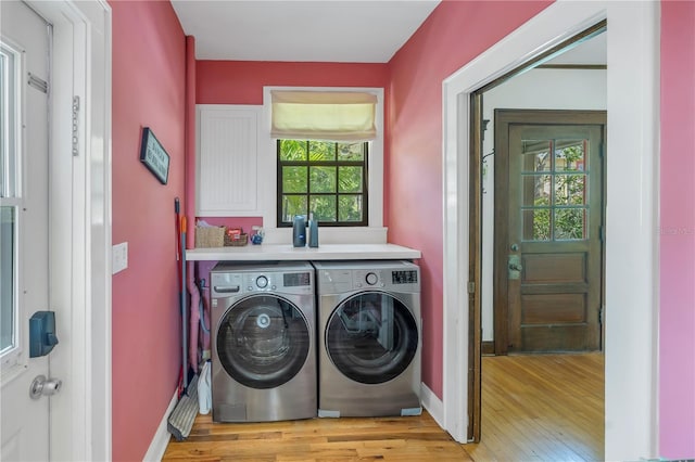 clothes washing area featuring washing machine and clothes dryer, cabinets, and light wood-type flooring