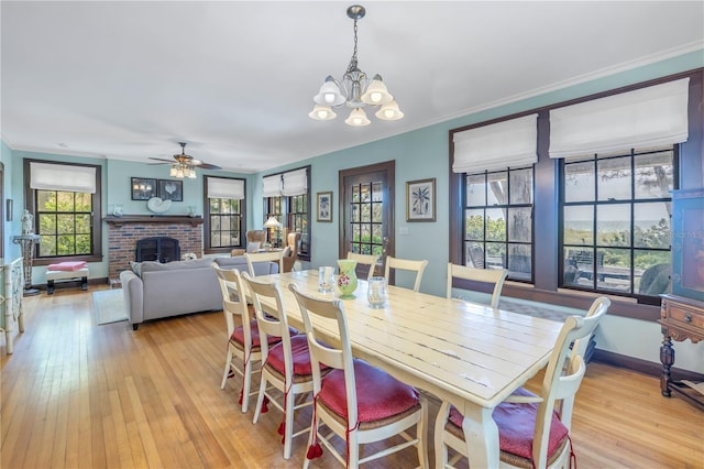 dining area with crown molding, light hardwood / wood-style flooring, a brick fireplace, and a healthy amount of sunlight