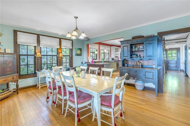 dining room featuring a wealth of natural light, an inviting chandelier, light hardwood / wood-style floors, and ornamental molding