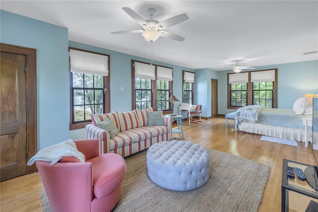 bedroom with ceiling fan, multiple windows, and light hardwood / wood-style floors