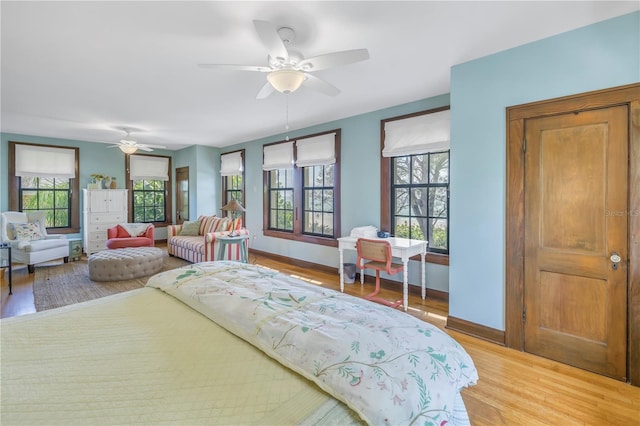 bedroom with multiple windows, wood-type flooring, and ceiling fan