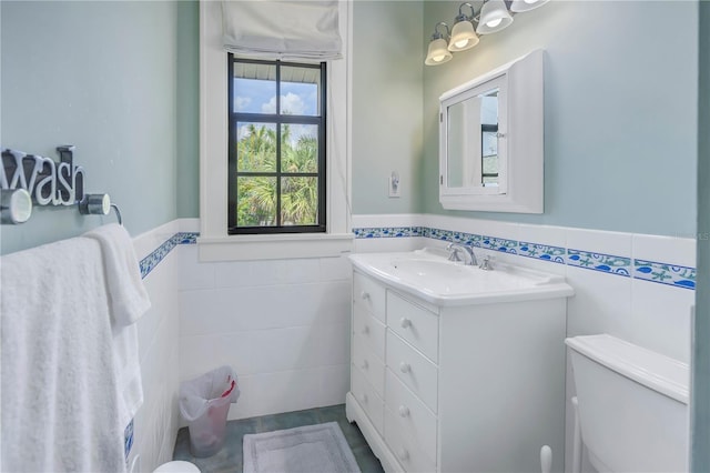 bathroom with vanity, tile walls, and toilet