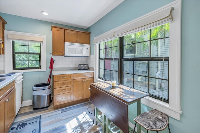 kitchen with backsplash, white appliances, and light hardwood / wood-style flooring