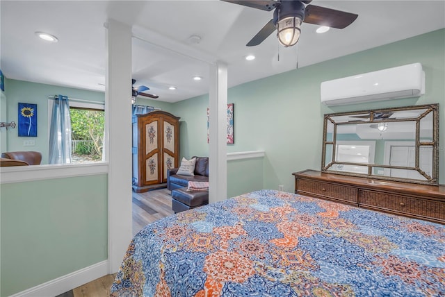 bedroom featuring ceiling fan, an AC wall unit, and light hardwood / wood-style flooring