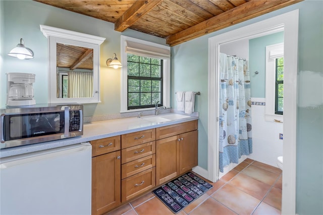 bathroom with wood ceiling, a wealth of natural light, beam ceiling, and tile patterned floors