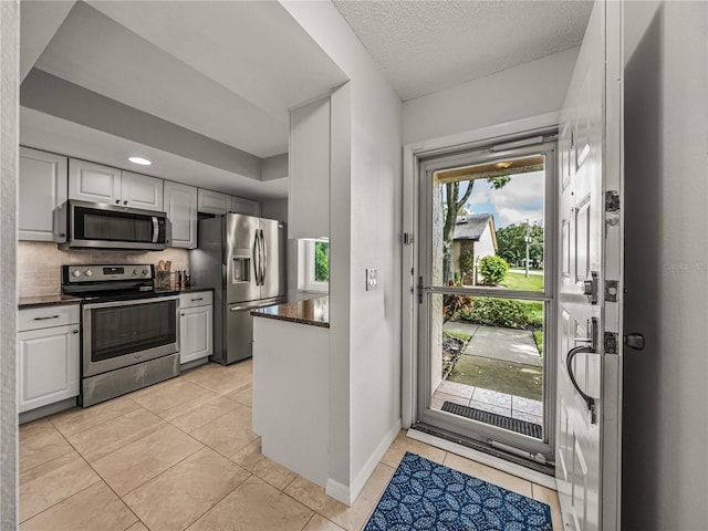 kitchen with a wealth of natural light, backsplash, light tile patterned floors, and appliances with stainless steel finishes