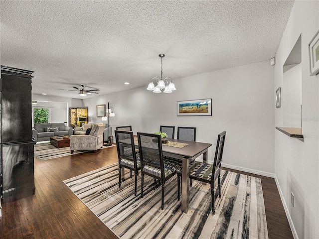 dining area with a textured ceiling, dark hardwood / wood-style floors, and ceiling fan with notable chandelier