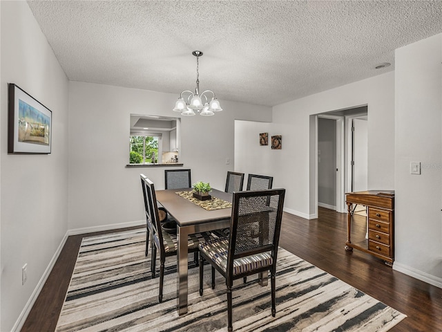 dining area with a textured ceiling, dark wood-type flooring, and a notable chandelier