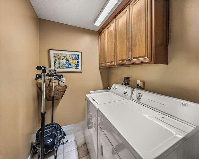 laundry area featuring light tile patterned floors, a textured ceiling, cabinets, and washer and dryer