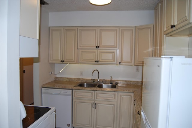 kitchen with white appliances, light stone counters, sink, and cream cabinetry