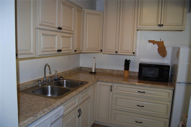 kitchen featuring white appliances, light stone countertops, sink, and cream cabinets