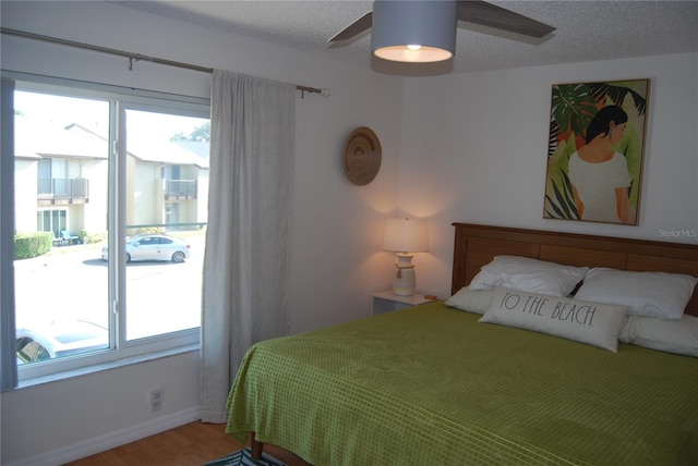 bedroom featuring multiple windows, ceiling fan, hardwood / wood-style flooring, and a textured ceiling