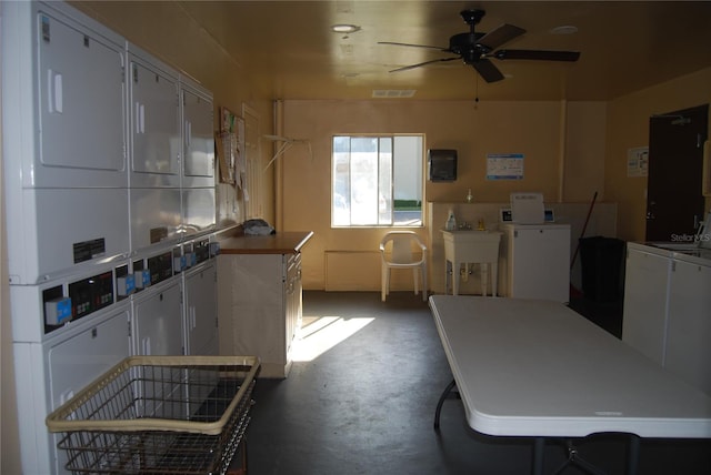 kitchen featuring white cabinets, ceiling fan, stacked washer / drying machine, and concrete flooring