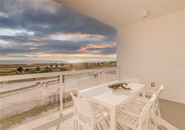 balcony at dusk featuring a water view