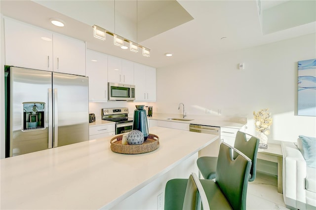 kitchen featuring light tile patterned floors, appliances with stainless steel finishes, white cabinetry, sink, and a breakfast bar