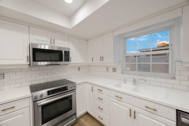 kitchen with stainless steel appliances, light wood-type flooring, backsplash, and white cabinets